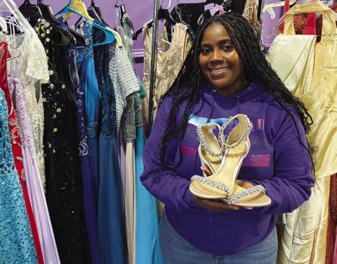 Reasha Daniels of Pretty Girlz Fitness in downtown Eatonton poses with just a few of the more than 200 formal dresses donated to provide local girls with prom and pageant gowns. IAN TOCHER/Staff