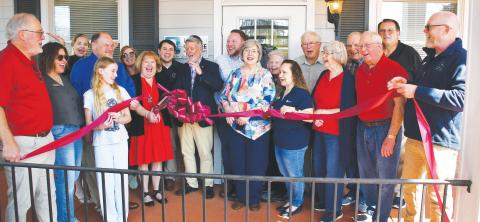 Licensed speech therapist Kay Jones (red dress), owner of Lake Oconee Speech Therapy, cuts the ribbon flanked by her husband and son as other members of her Lake Country community cheer the official opening of her facility at 951 Harmony Rd., Ste. 103, Eatonton. IAN TOCHER/Staff