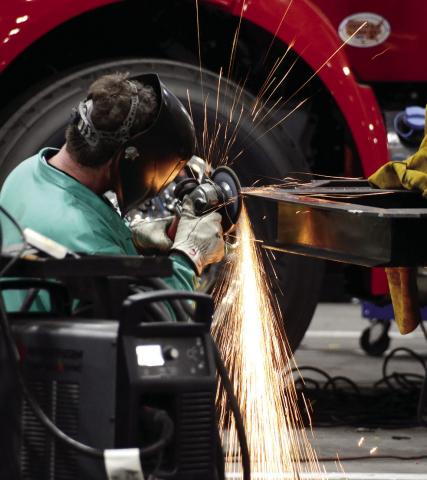 Sparks fly as a Fouts Bros. worker uses a grinder on the frame of a firetruck. IAN TOCHER/Staff