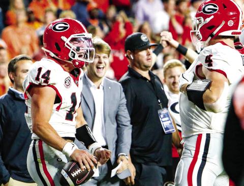 Georgia quarterback Gunner Stockton (left) celebrates with tight end Oscar Delp (right) after icing the game with a 10-yard touchdown run late in the fourth quarter against Auburn. LANCE McCURLEY/Staff