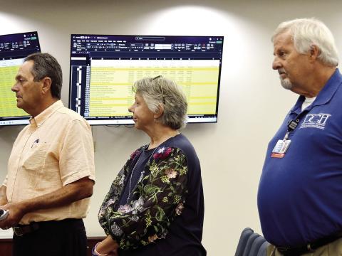 L-R: Putnam General Hospital Authority Board member Lou Benjamin, PGH Human Resources Director Rhonda Largo, and hospital CEO Alan Horton address county commissioners with detailed financial stats displayed on screens behind them. IAN TOCHER/Staff
