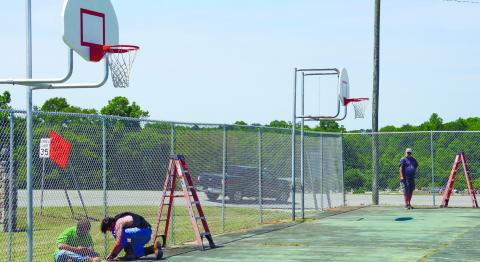 Putnam County contract workers put the finishing touches on a new fence last Wednesday, surrounding the basketball courts at Jimmy Davis Park. IAN TOCHER/Staff
