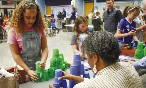 A Speed Stack Club member shows board member Simone Jones how to stack the cups. BAILEY McCULLY/Staff