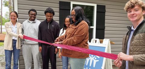 L-R: Habitat for Humanity of Putnam’s Katherine Mahlberg with new homeowners Jaevien, Khaleb, Amyah, and Candice Ellison cutting the ribbon May 12, as GCSU student and HFHP volunteer Zach Zachry keeps it tight. IAN TOCHER/Staff
