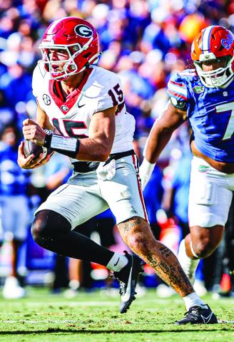 Georgia quarterback Carson Beck (15) shakes a defender in last year’s contest. KARI HODGES/UGAAA