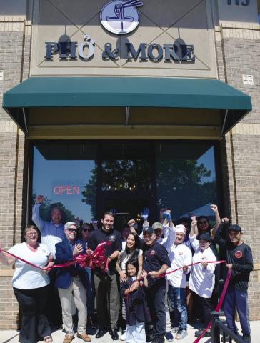 Pho & More co-owner Marino Graf (with scissors) stands with his wife, Summer, her father, John Nguyen, and the couple’s daughter while friends and employees help them celebrate during a ribbon-cutting ceremony hosted by the Eatonton-Putnam Chamber of Commerce. IAN TOCHER/Staff