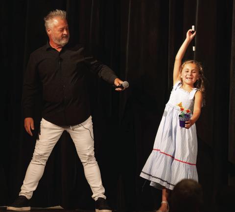 Mark the Magic Man’s daughter performs a trick from the magic wand that produces flowers. She learned this trick at his magic camp. LEIGH LOFGREN/Staff