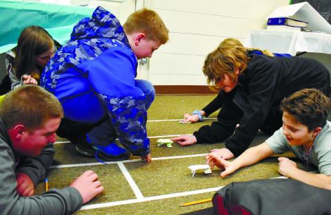 Three teams put their origami frogs to the test in the race trying to see which one will leap farther and faster.
