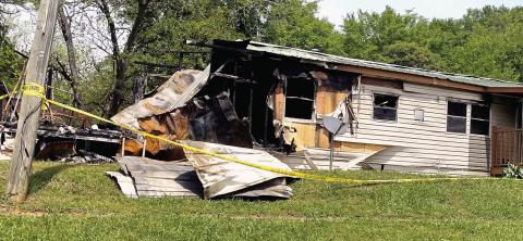 Yellow crime tape surrounds the burned mobile home on East Marion Street Monday. The left side of the home was completely burned away, and the rest of the interior gutted and/or charred by the flames. LYNN HOBBS/Staff