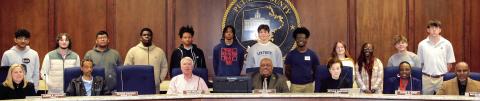 Twelve members of the 2024 Eatonton Youth Leadership Class from Gatewood and Putnam High Schools line up behind Eatonton City Council members during a Feb. 19 council meeting. IAN TOCHER/Staff