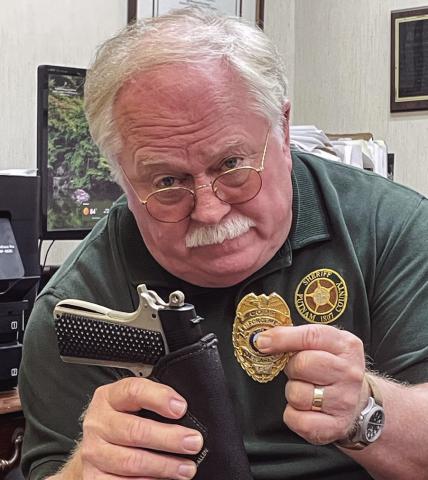 Putnam County Sheriff Howard Sills’ facial expression doesn’t hide his feelings on this holstered BB gun pistol and altered law enforcement badge used in several crimes in and around Putnam County. LYNN HOBBS/Staff