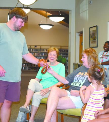 Program Specialist Walker Boswell hands a snake to participants of the Summer Reading program. (SHELBY HUCKABY/Staff)