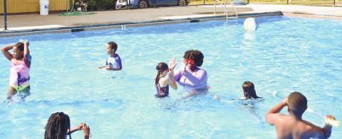 Camp instructor Rakeena Griffin high-fives third-grader Skylar Bridges, who just successfully swam up to her covering some distance in water.