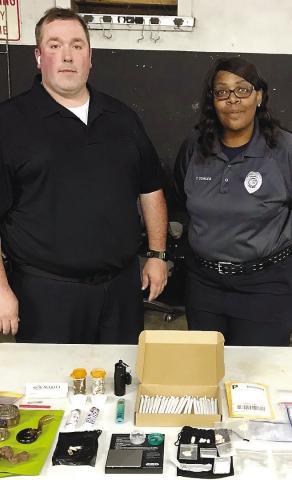 Eatonton Police Department’s officer Alex Rickey and office staff member Tammi Towles stand with the many drugs and drug paraphernalia they inventoried from a traffic stop Rickey made. CONTRIBUTED/EPD