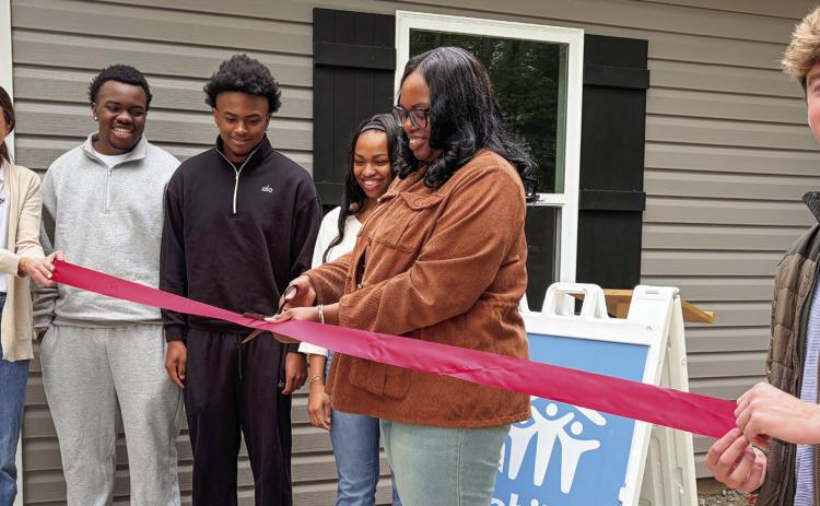 L-R: Habitat for Humanity of Putnam’s Katherine Mahlberg with new homeowners Jaevien, Khaleb, Amyah, and Candice Ellison cutting the ribbon May 12, as GCSU student and HFHP volunteer Zach Zachry keeps it tight. IAN TOCHER/Staff